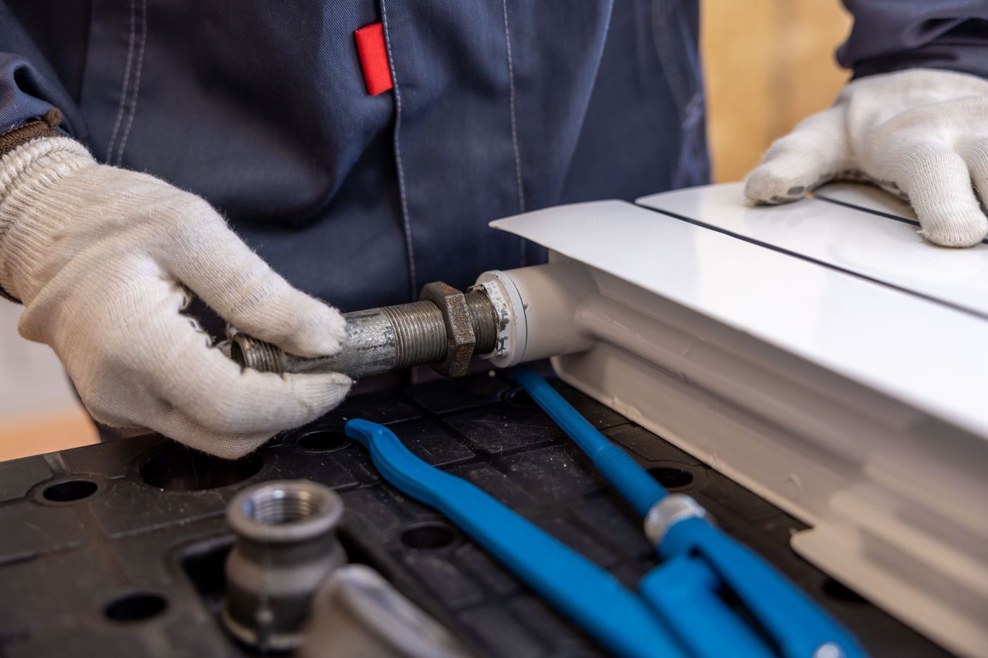 Handschoenen monteren een leiding aan een radiator met blauwe pijpen
