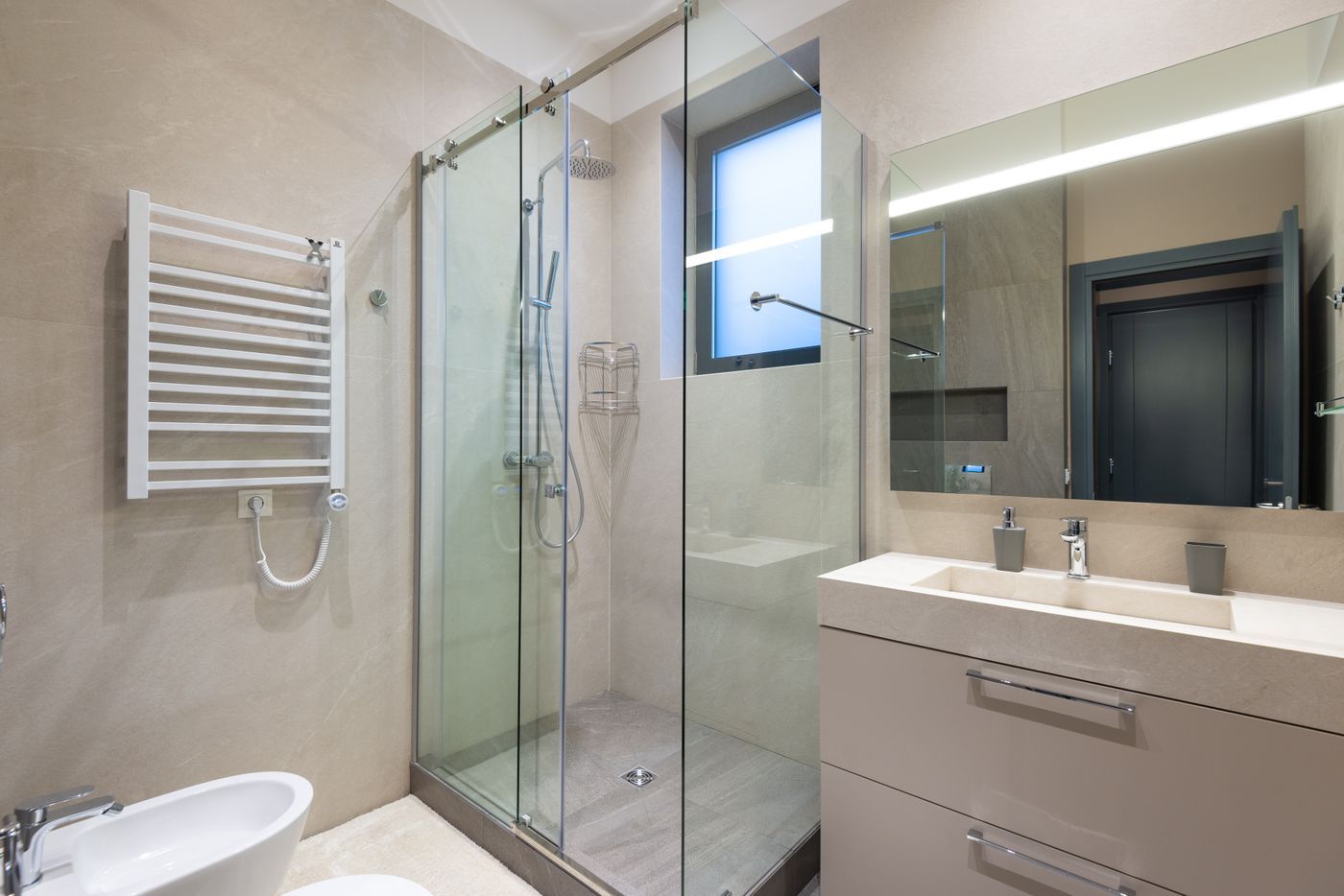 Badkamer met glazen douche en handdoekradiator in lichte tinten